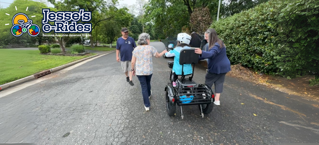 Miriam rides the Meet One Breeze Pro e-trike, with her mom walking nearby and a Jesse’s e-Rides team member looking on.